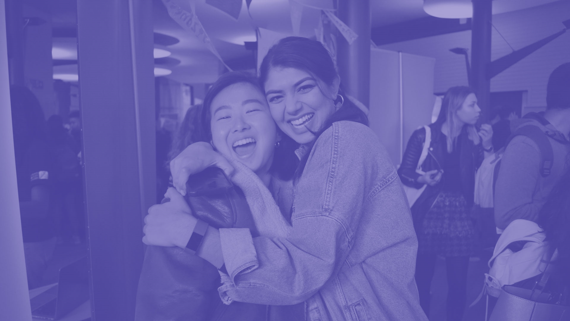 Two students smiling and hugging each other