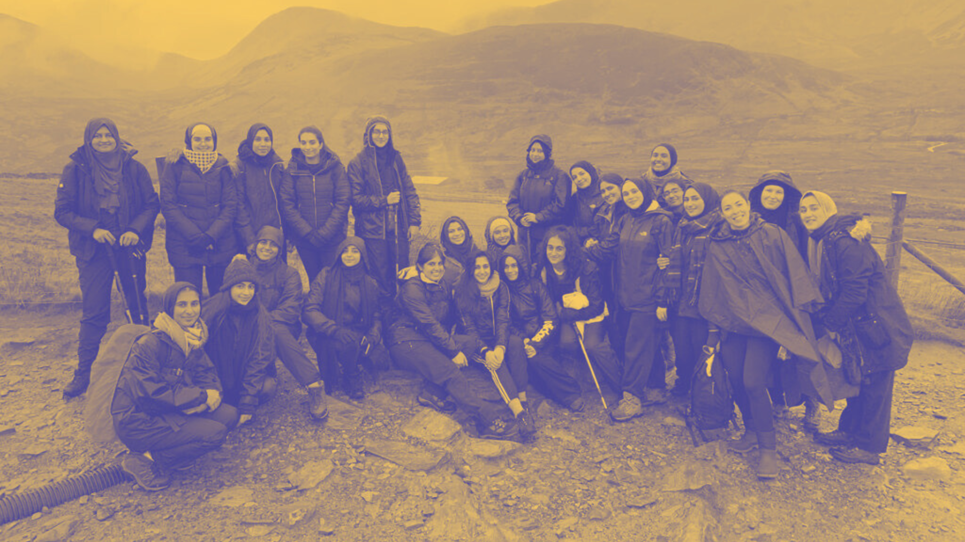 A student group getting a group photo taken on a trip to a mountain range
