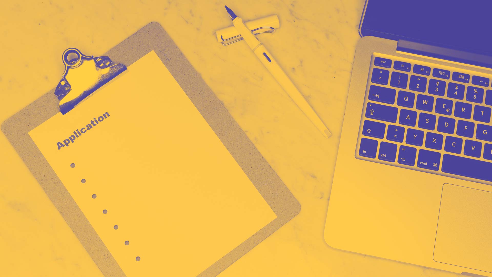 A funding application on a desk next to a laptop and pen