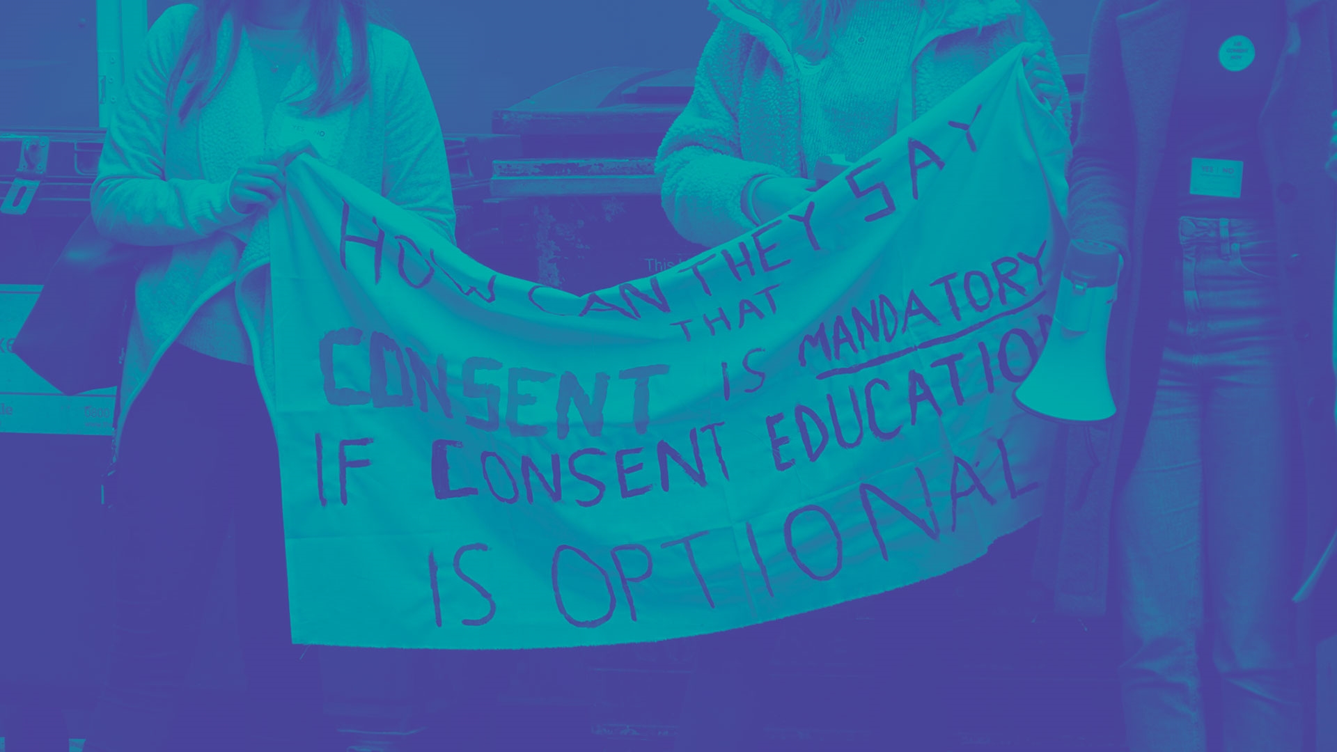 Students holding a banner that reads 'how can they say consent is mandatory if consent education is optional?'