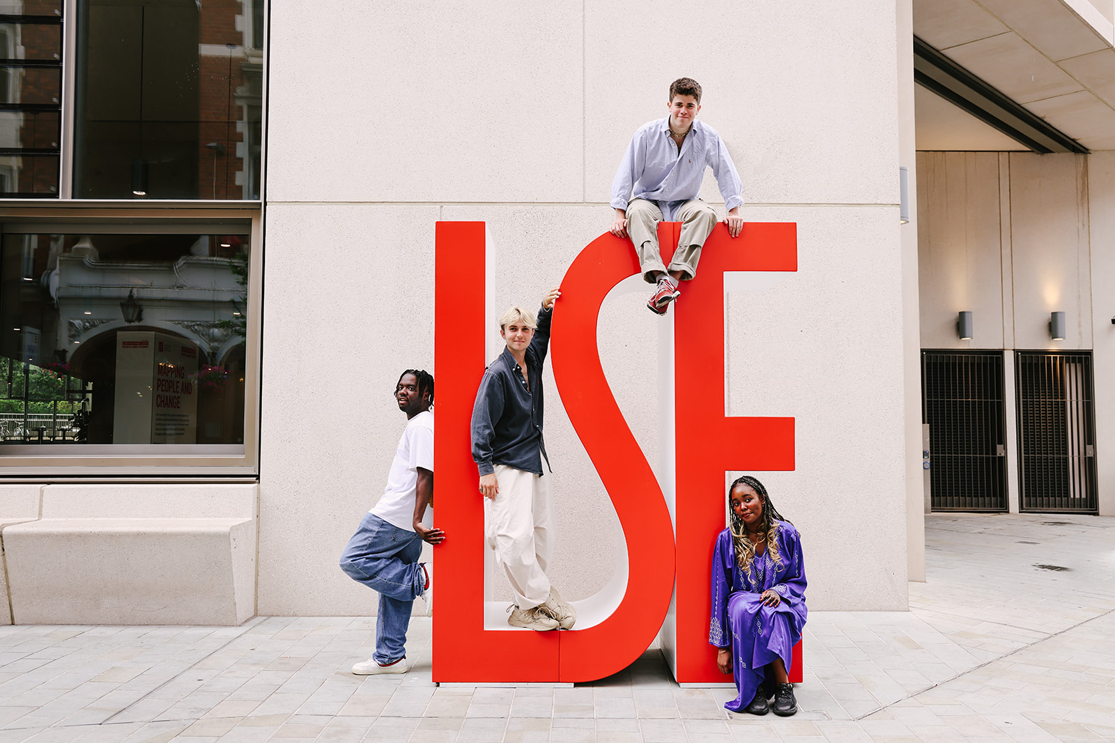 Students leaning on giant red letters saying LSE