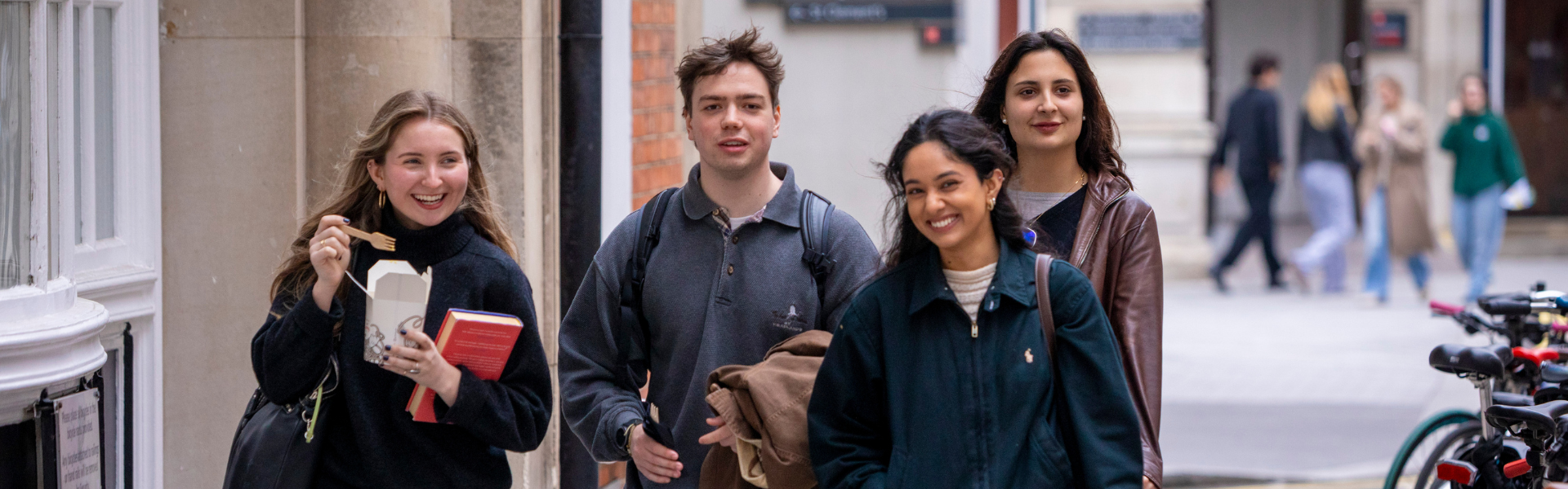 Four students walking through campus talking