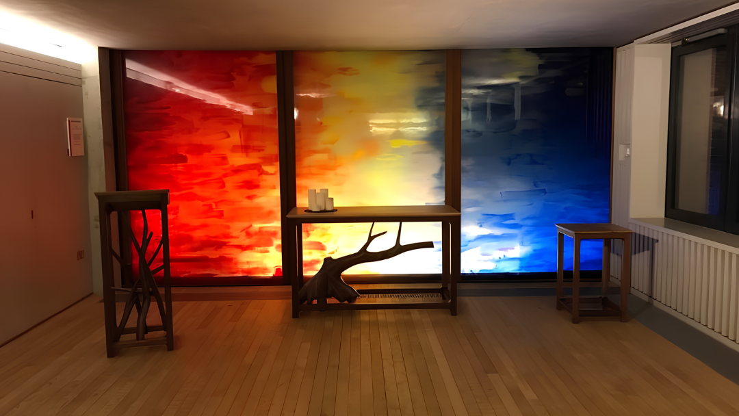 A photograph of a colourful wall in the faith centre with calm, dim lighting and candles