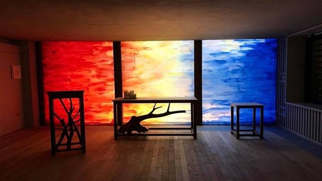 A photograph of a colourful wall in the faith centre with calm, dim lighting and candles