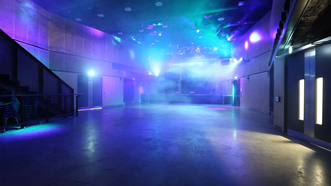 A shot of The Venue showing blue event lights lighting up smoke through the room like a club